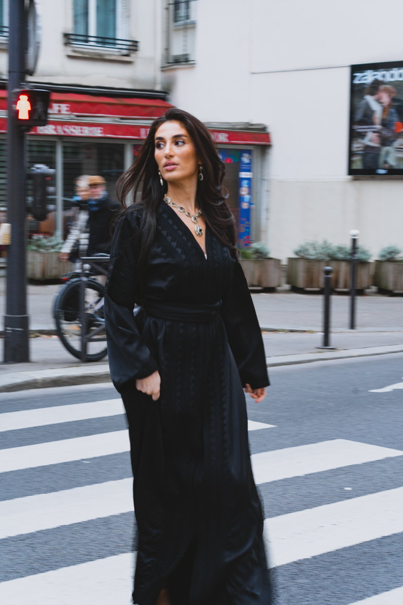 Une femme traverse un passage piéton et porte un caftan marocain noir en drap de soie