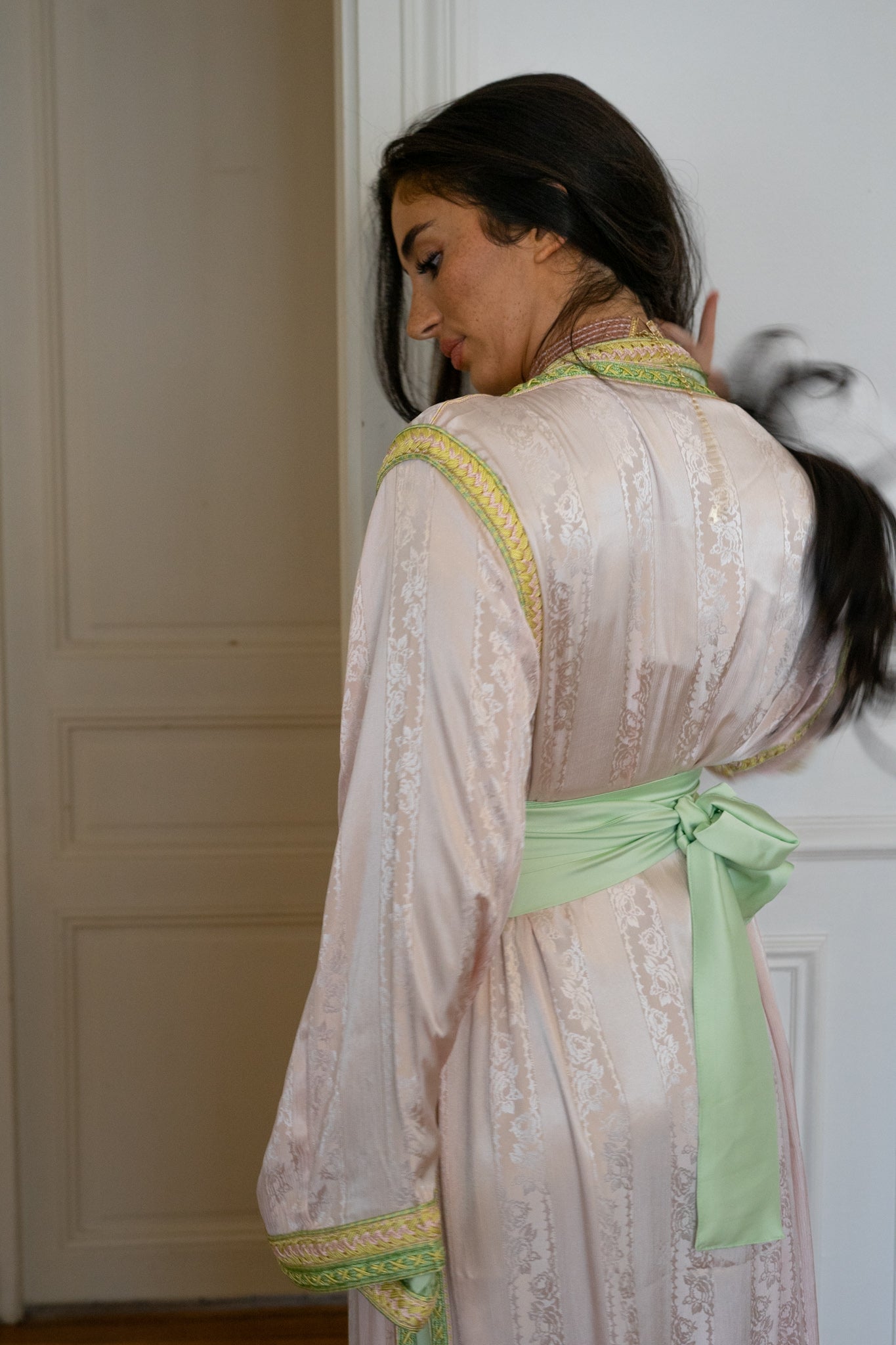 Prise de dos d'une takcita marocaine pour mariage de couleur rose et verte avec ceinture en tissu
