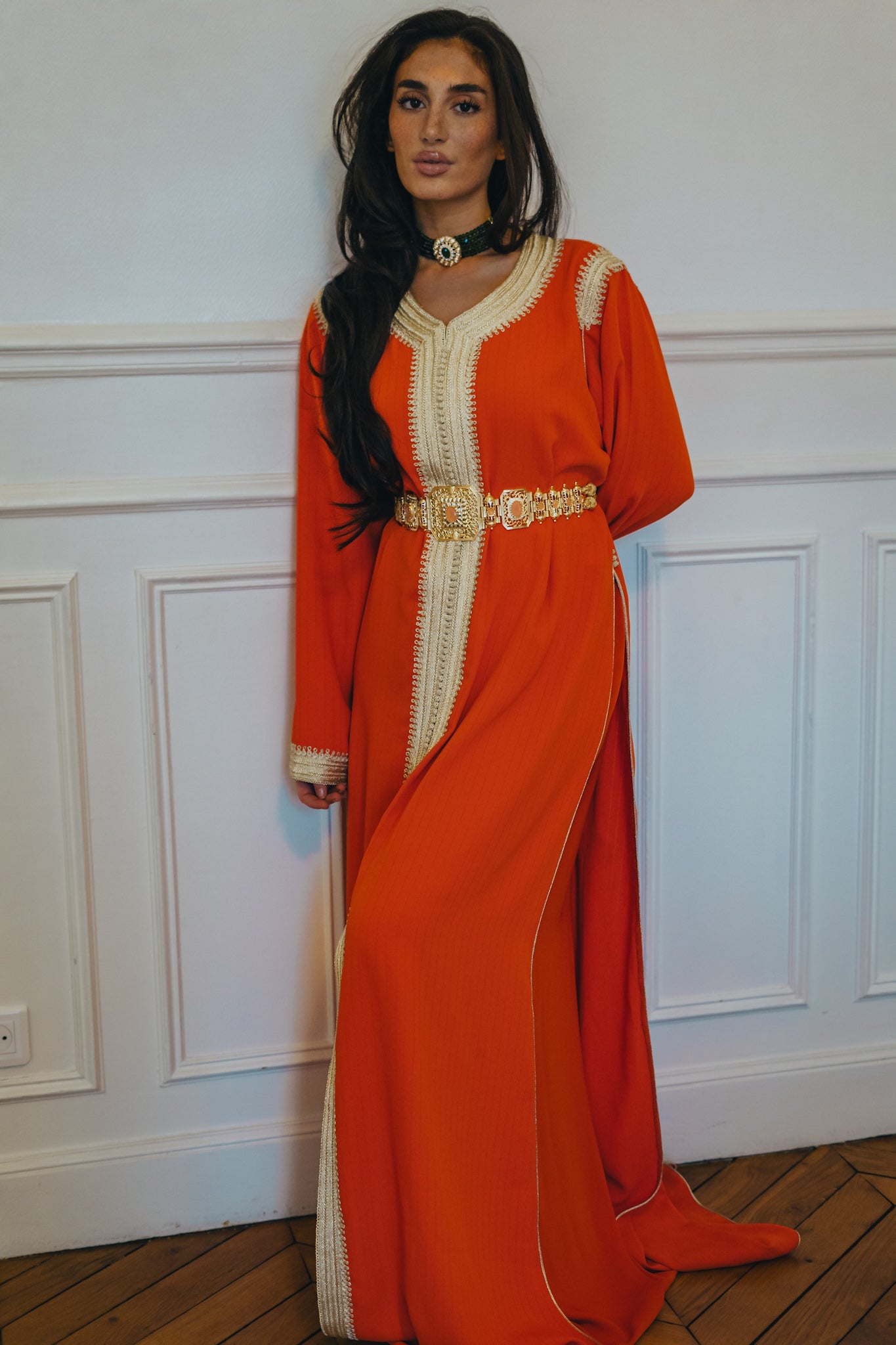 Femme portant un caftan orange et une ceinture dorée